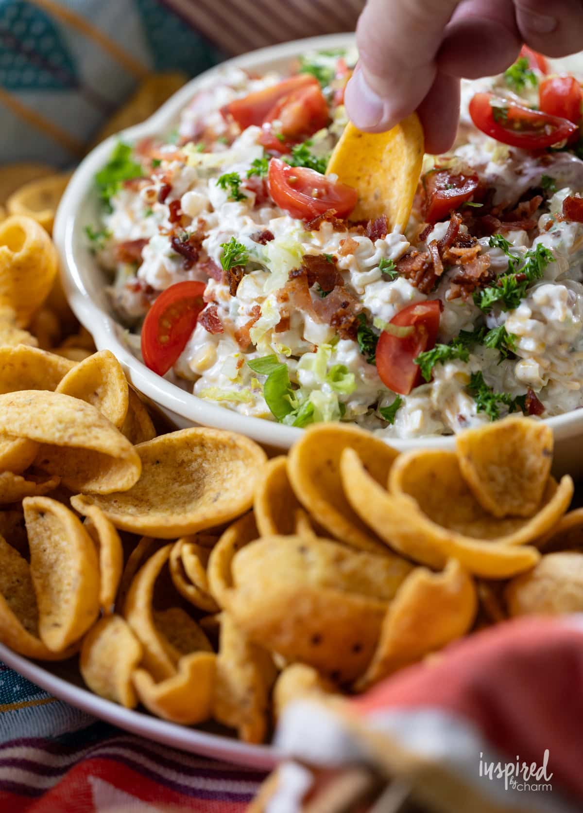 hand with a frito scoop taking a bite of BLT Corn Dip.