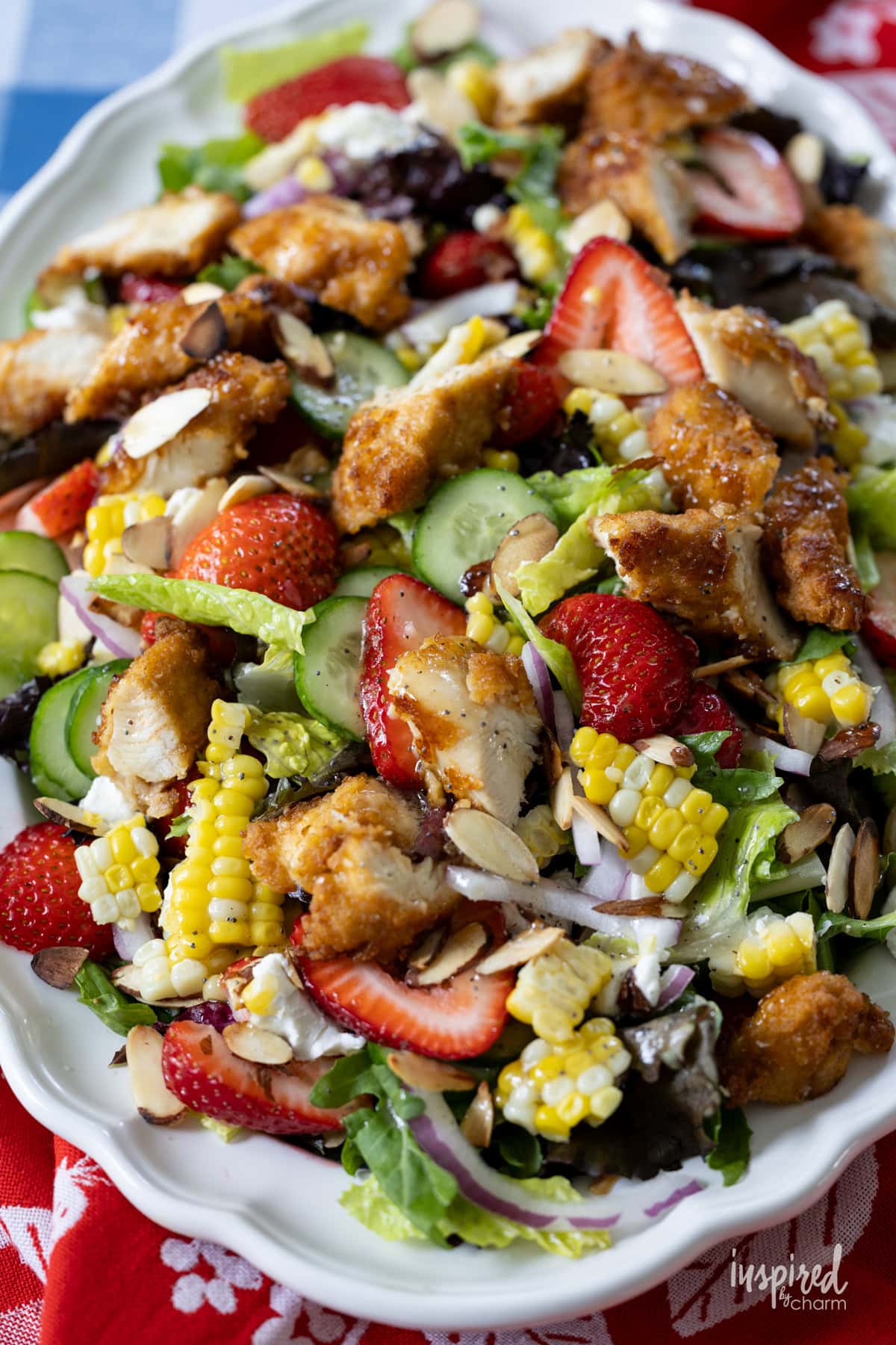 big salad on a platter filled with ingredients on a table.