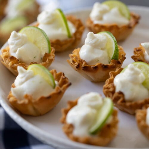 Key Lime Pie Tartlets on a white cake stand.