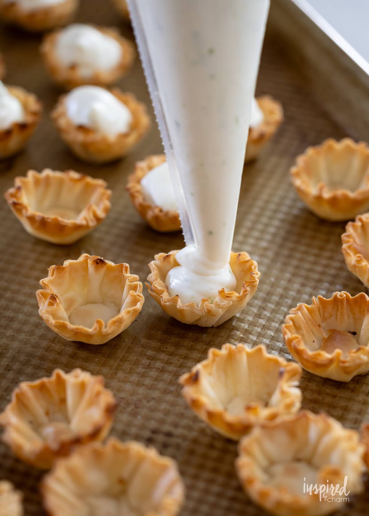 piping bag filling phyllo shells with key lime pie filling.