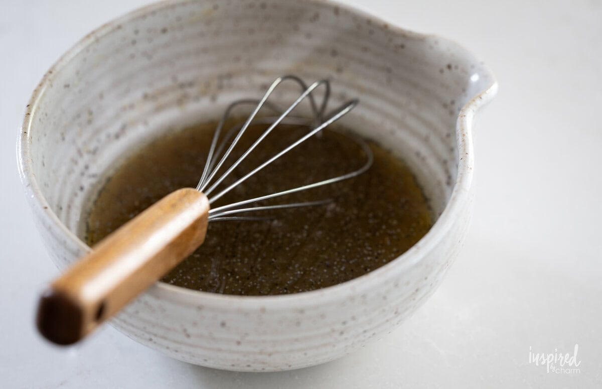 honey poppyseed vinaigrette in bowl with a whisk.