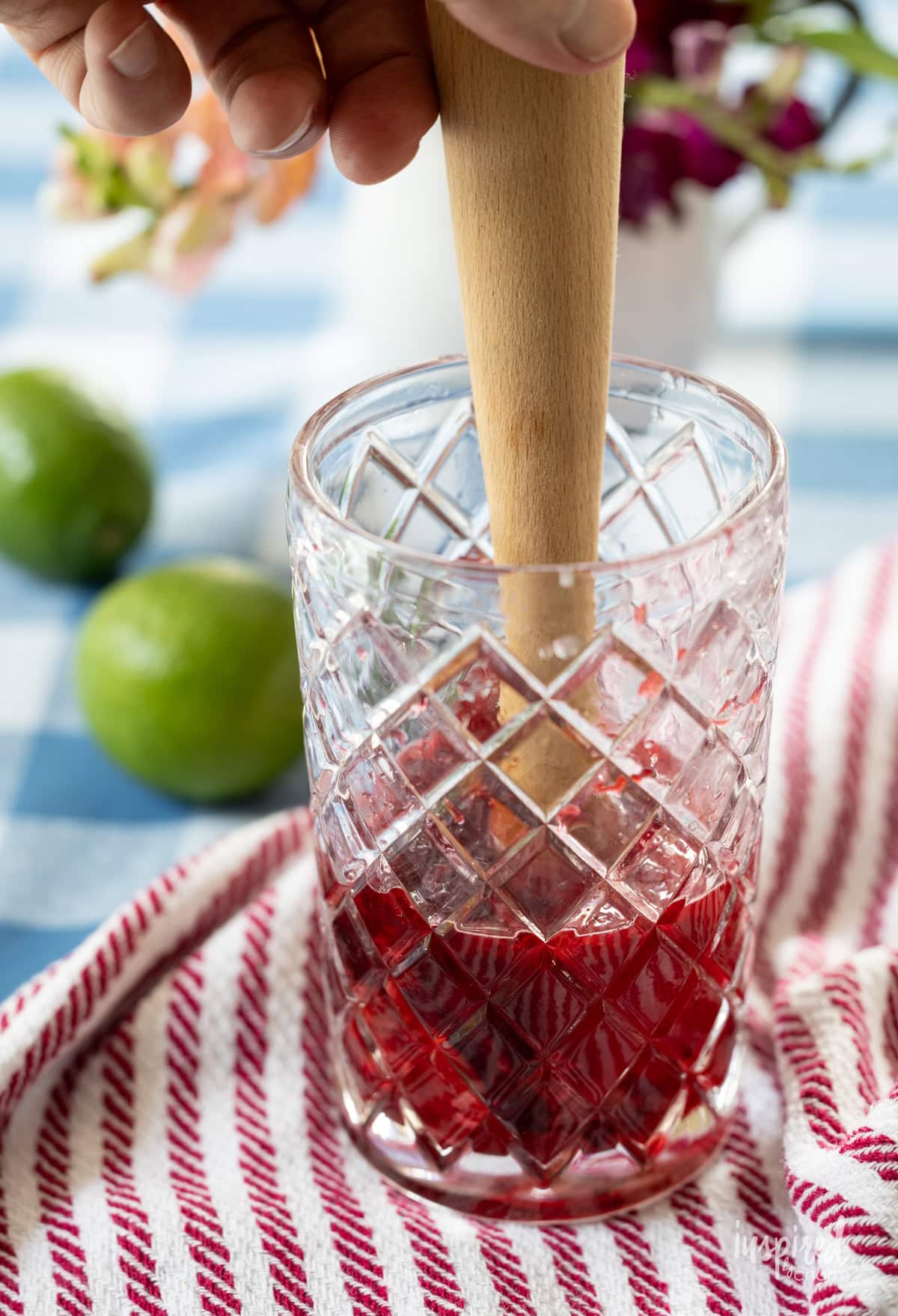 muddler in a glass with cherries.