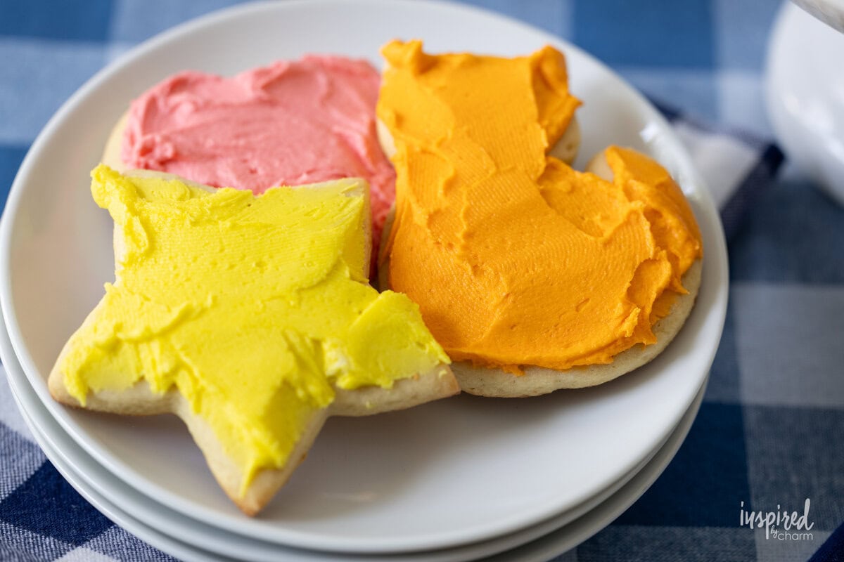 three frosted sugar cookies on a small plate.