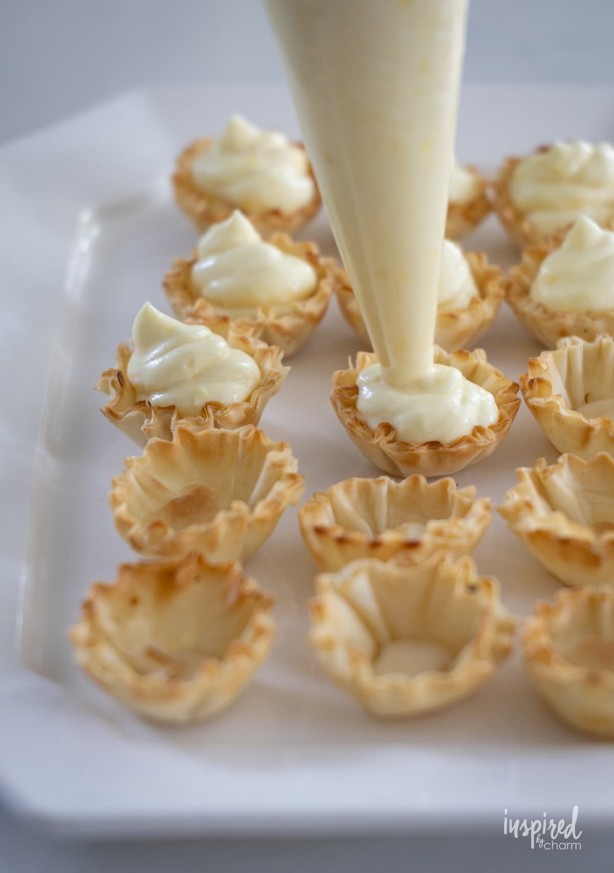 piping bag adding coconut filling to phyllo shells. 