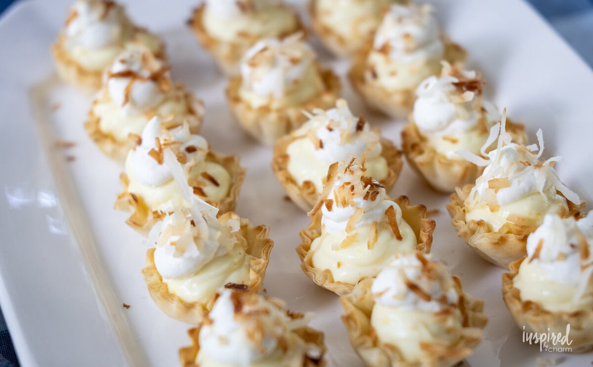 rows of Mini Coconut Cream Pie Tartlets on a white platter. 