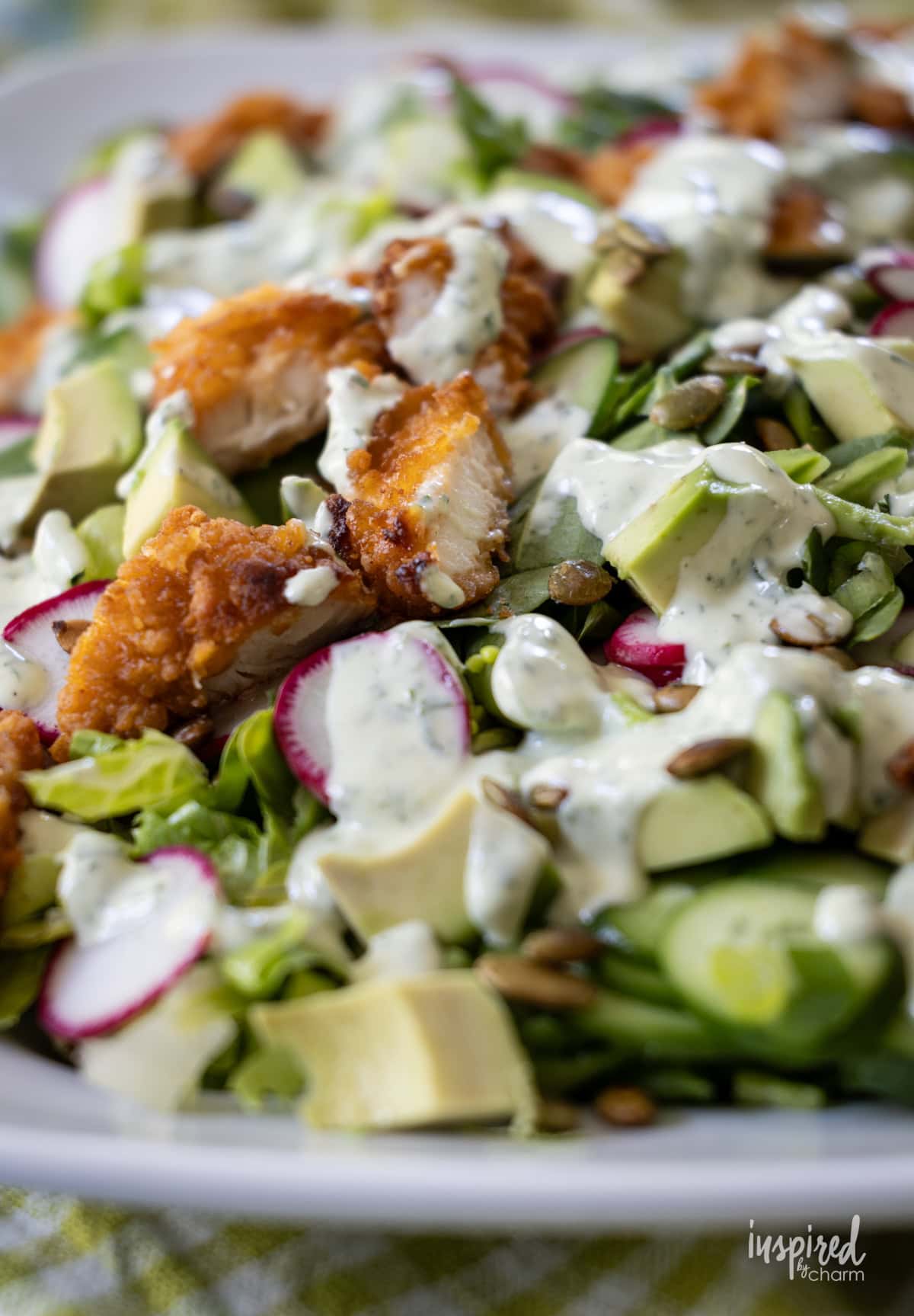 green goddess salad with dressing on white platter.