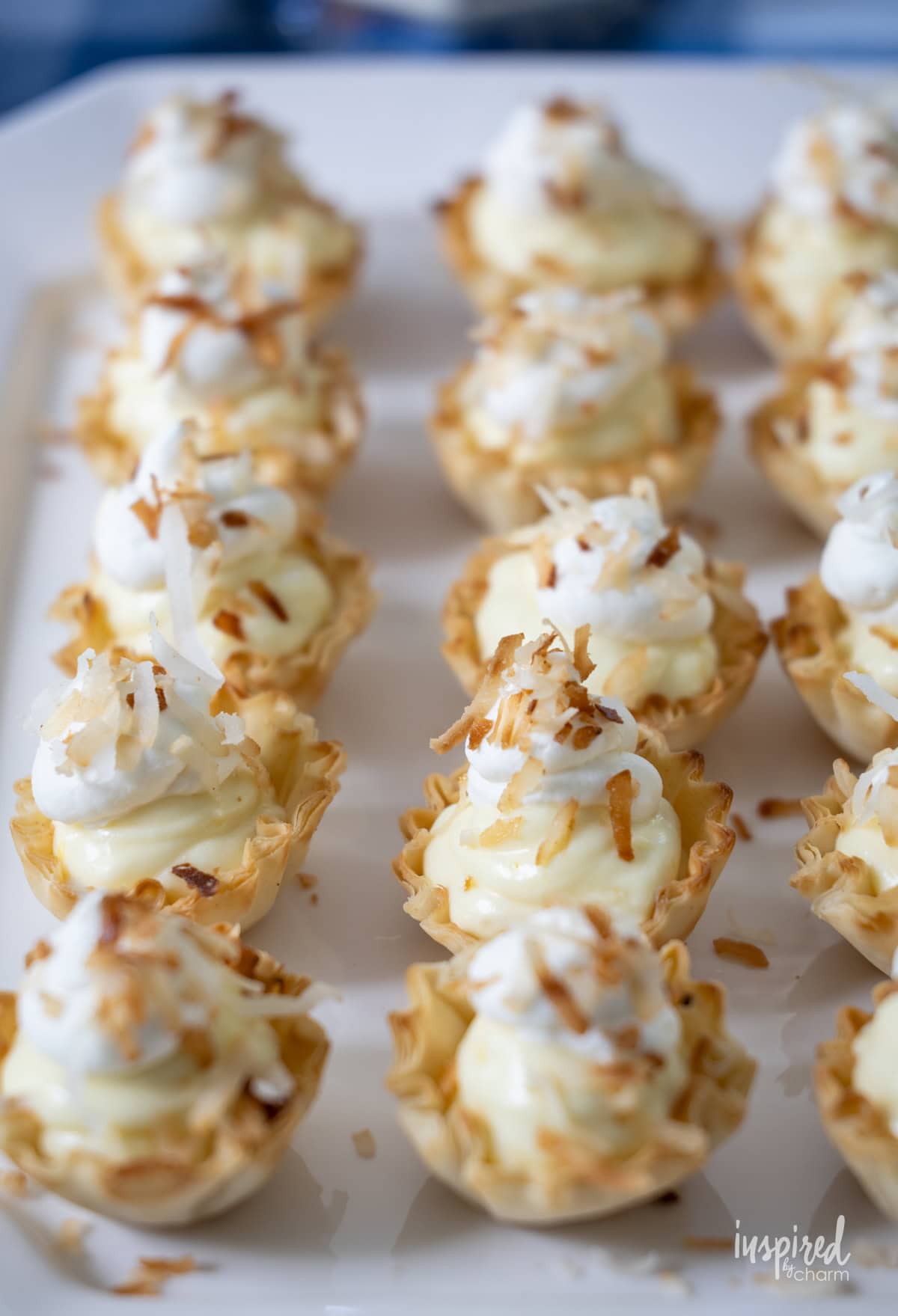 Mini Coconut Cream Pie Tartlets in a row on a plate.