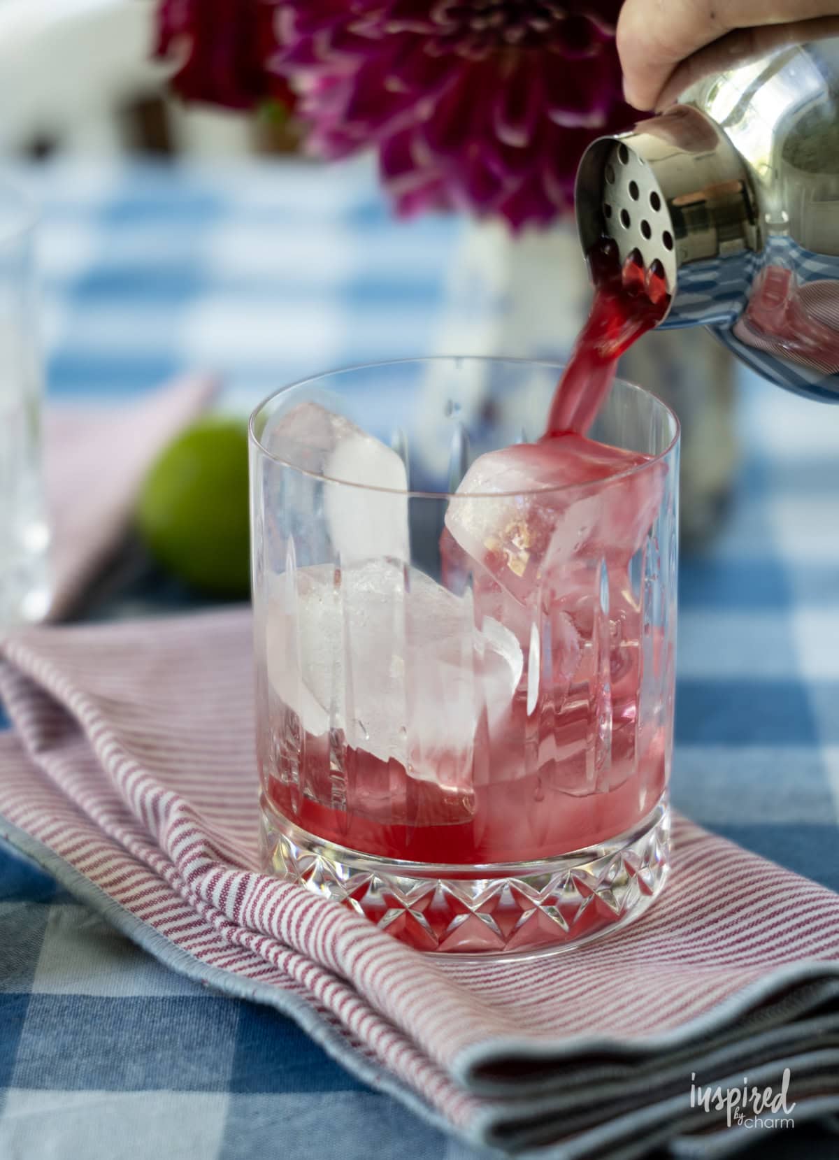 Strainer pouring Cherry Pineapple Cooler into glass with ice.