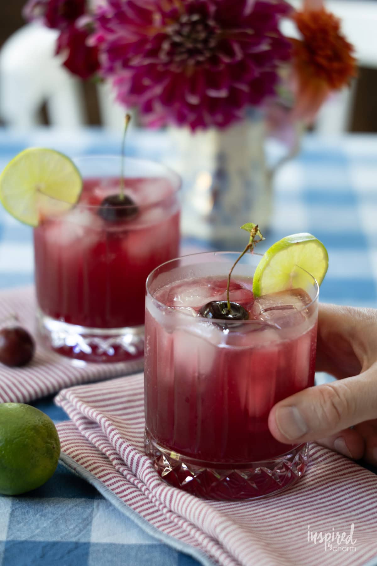 hand holding a glass of Cherry Pineapple Cooler on a table. 