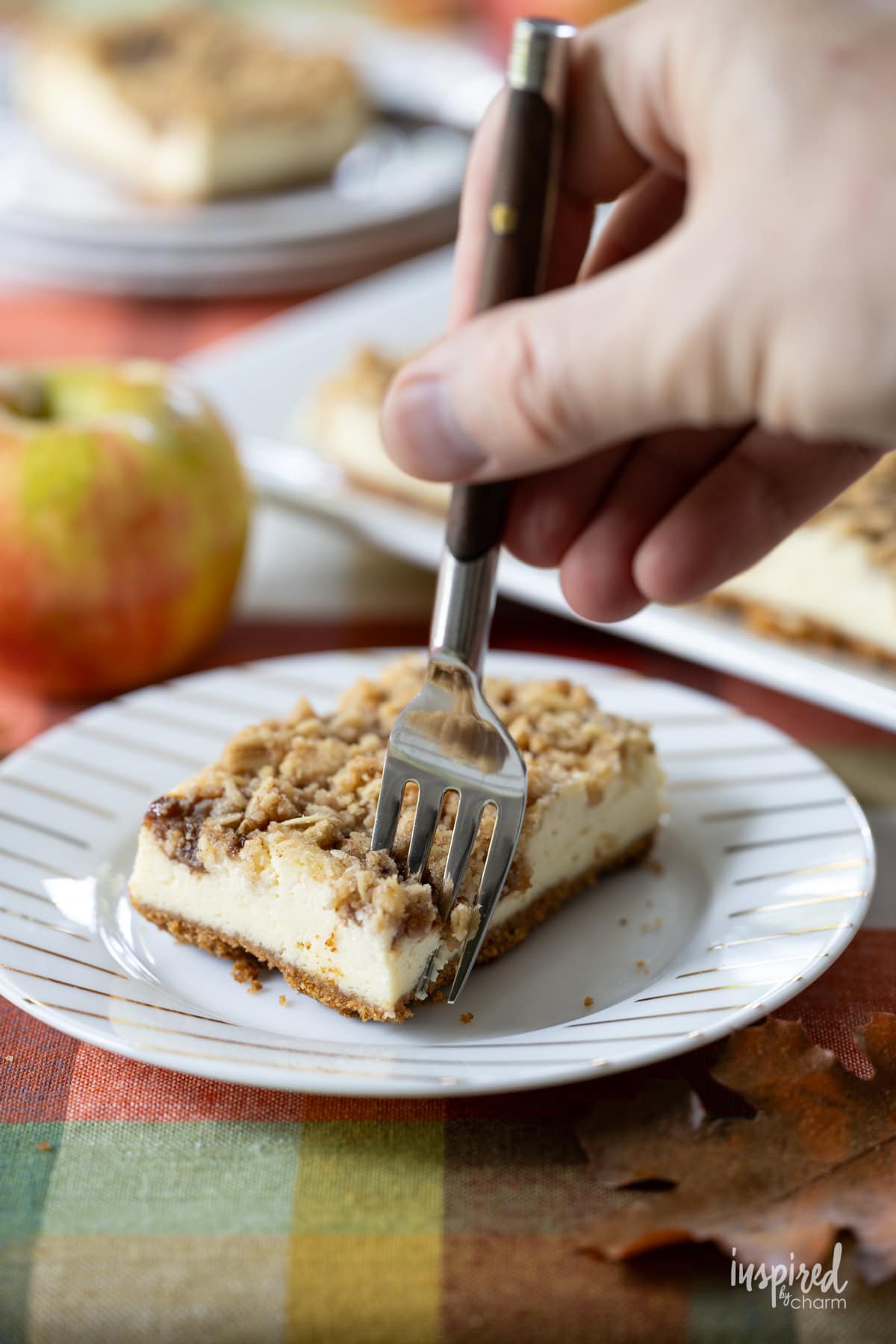 hand with fork take a bite of Apple Butter Cheesecake Bars.
